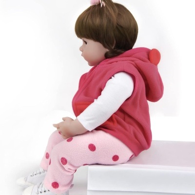 Boneca vestida de vermelho e rosa sentada numa caixa branca