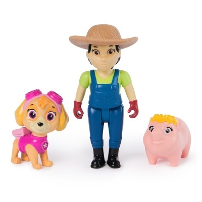 Três brinquedos plásticos incluindo cão castanho com acessórios rosa, figura humana com chapéu e porco rosa com cabelo amarelo