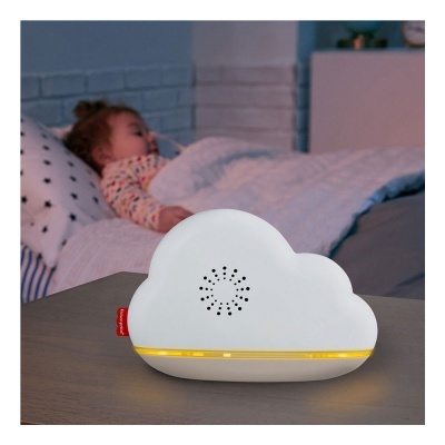 Dispositivo em forma de nuvem branco com luz amarela na base sobre mesa junto a cama com criança a dormir