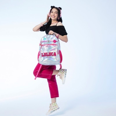 Moça sorridente com mochila holográfica LUDCA e roupa colorida