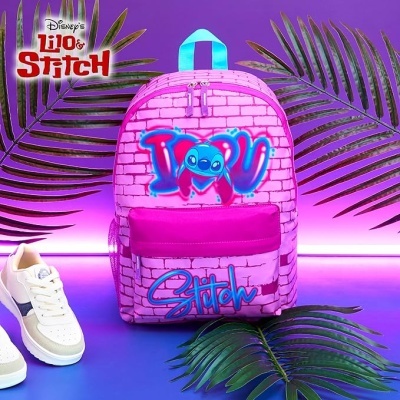 Mochila infantil rosa com estampa do Stitch azul e texto, em cenário com folhas verdes e sapatilhas brancas