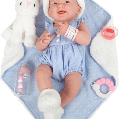 Boneco bebé vestido com azul e touca com orelhas de urso, deitado numa manta azul com brinquedos e peluche branca