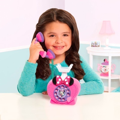 Telefone de brinquedo cor de rosa com personagem Minnie Mouse e criança a brincar