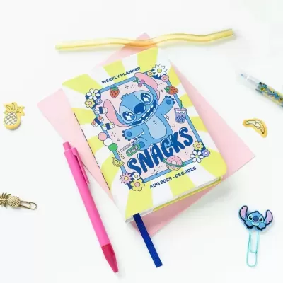 Planificador semanal com capa azul e amarela com personagem Stitch, caneta rosa e clips decorativos