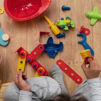 Peças de brinquedo de construção coloridas e criança a brincar no chão de madeira