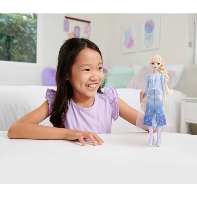 Menina sorridente brinca com boneca Elsa da Disney num quarto com decoração pastel