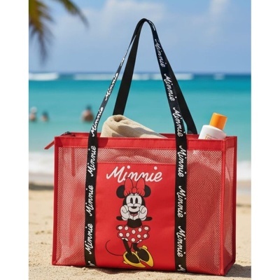 Sacola de praia vermelha da Minnie com alças pretas, preenchida com toalha e frasco, na praia.