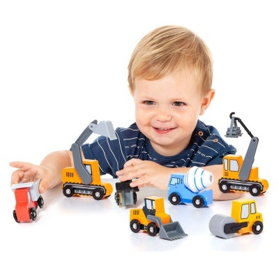 Criança a brincar com carrinhos de construção em madeira coloridos sobre fundo branco