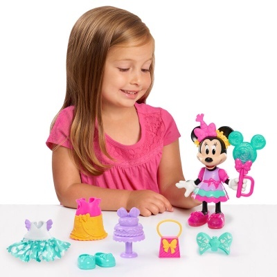 Boneca Minnie com acessórios coloridos sobre mesa branca, menina ao fundo