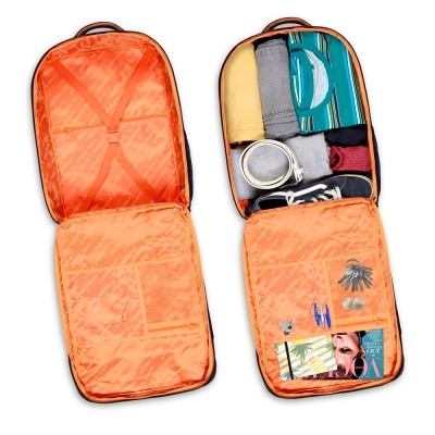 Mala de viagem laranja aberta mostrando roupa e acessórios organizados