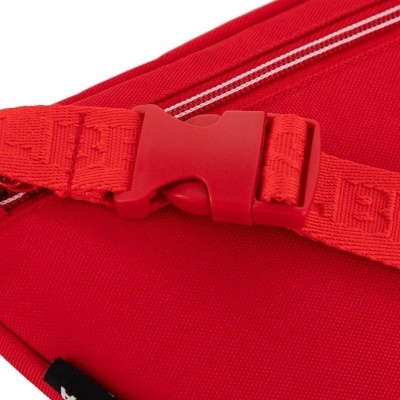 Parte de mochila vermelha com fecho plástico e fita com padrão.