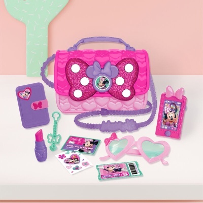 Conjunto infantil rosa e violeta com bolsa, acessórios de brincar e óculos em forma de coração.