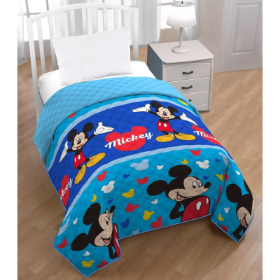 Edredom azul com personagens do Mickey em cama branca em quarto com chão de madeira e mesa de cabeceira