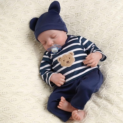 Bebé a dormir com roupa azul e branca, gorro com orelhas, sobre manta creme trançada