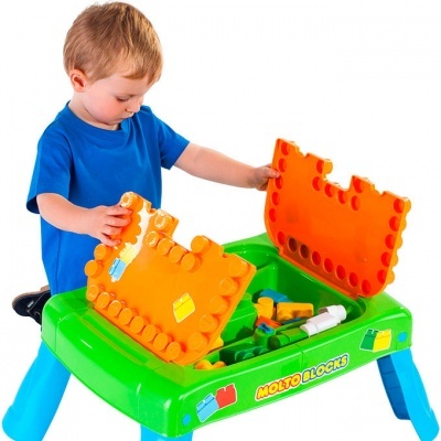 Criança a brincar com mesa verde de blocos de construção com tampas alaranjadas