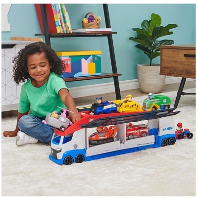 Criança a brincar com caminhão de transporte de carros de brinquedo colorido no chão}