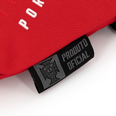 Etiqueta preta com texto 'PRODUTO OFICIAL' numa peça de tecido vermelho.