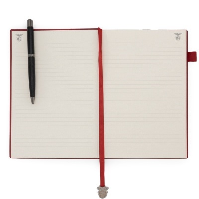 Caderno aberto com páginas pautadas, marcador vermelho e caneta preta ao lado