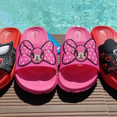 Chinelos rosa e vermelhos com temas da Disney junto a piscina
