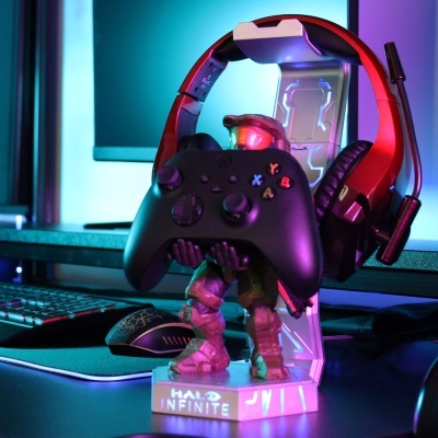 Figura de ação Halo Infinite com comando de videojogo e auscultadores vermelhos numa base iluminada