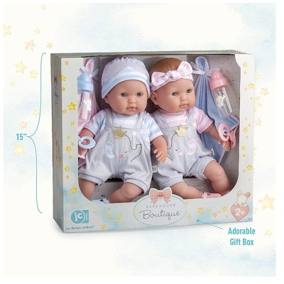 Dois bonecos bebés na caixa com roupas cinza e acessórios rosa e azul.