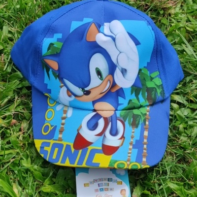 Boné azul com personagem Sonic e texto SONIC, sobre relva verde