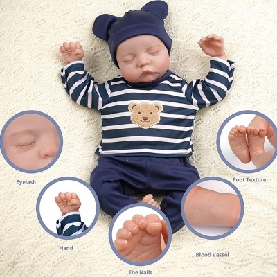 Boneco bebé realista vestido com roupa azul e branco, detalhes ampliados das mãos, pés e rosto
