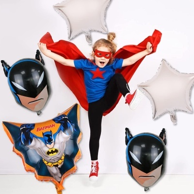 Criança com traje azul e vermelho e balões de Batman ao fundo