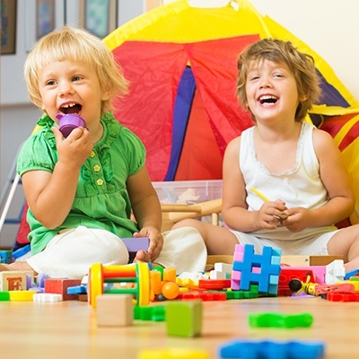 Duas crianças brincando com blocos de construção multicoloridos no chão em frente a uma tenda colorida