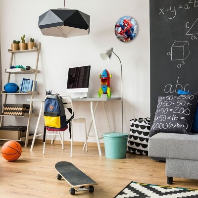 Quarto ou escritório infantil com mesa, cadeira, computador, mochila, bola de basquetebol, skate, almofadas, sofá cinza, quadro-negro com fórmulas e relógio do Homem-Aranha