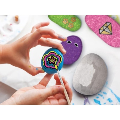 Mãos a pintar pedra azul com padrão de flor colorida