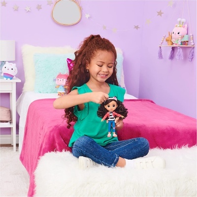 Menina a brincar com boneca no quarto colorido lilás e rosa