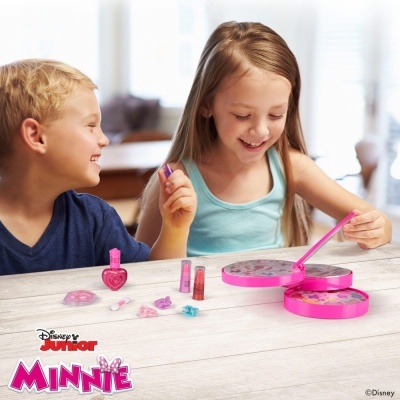 Crianças a brincar com maquilhagem em caixa rosa numa mesa de madeira clara