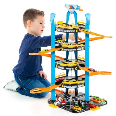 Menino a brincar com parque de estacionamento de brinquedo azul e laranja com rampas e carrinhos.