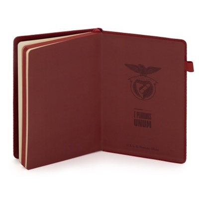 Caderno vermelho aberto com emblema e texto na capa interior