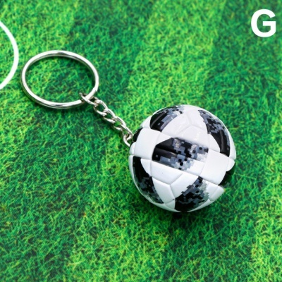 Porta-chaves com bola de futebol preto e branco sobre fundo verde de relva