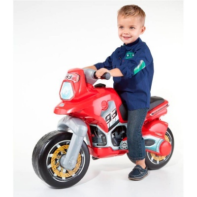 Menino em mota de brinquedo vermelha com número 93 em fundo branco