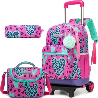Conjunto mochila rosa com corações verdes e manchas azul marinho, estojo e saco da mesma cor, com pendente pompom verde claro