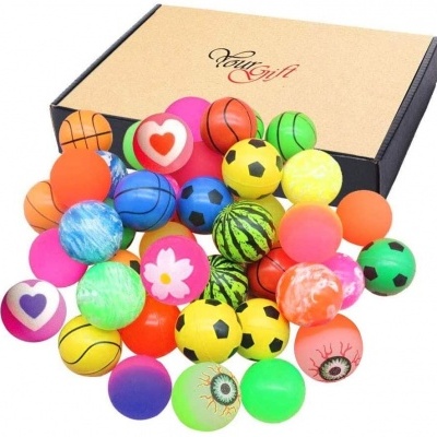 Várias bolas coloridas de borracha com padrões variados diante de uma caixa de cartão