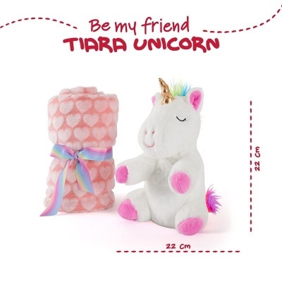 Peluches em forma de unicórnio branco ao lado de uma manta rosa com corações brancos e uma fita arco-íris.