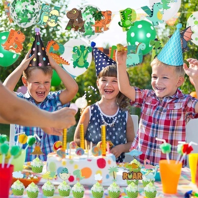 Crianças numa festa de aniversário ao ar livre com decoração de dinossauros e bolo colorido