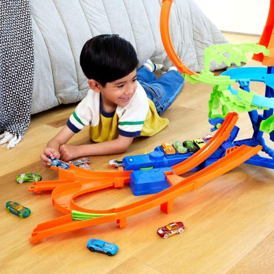 Criança a brincar com pista de carrinhos colorida e carrinhos de brinquedo no chão