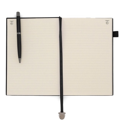 Caderno aberto com páginas forradas a linhas e caneta preta colocada