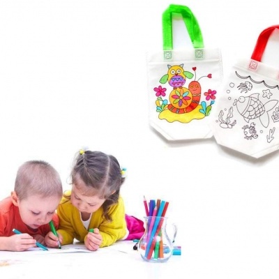 Crianças a pintar no chão com duas bolsas de tecido com desenhos penduradas