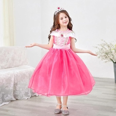 Menina vestida de princesa com vestido cor-de-rosa, coroa e sapatos brilhantes