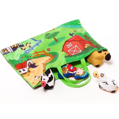 Livro de tecido com ilustração de quinta e quatro bonecos de peluche de animais.