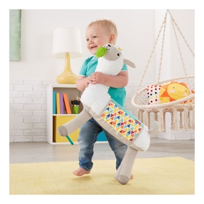 Criança a segurar peluche em formato de lhama numa sala de estar com tapete amarelo e estante branca