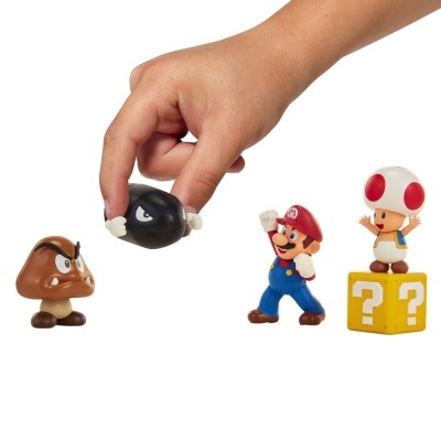 Figuras de brinquedo dos personagens Super Mario com uma mão segurando a figura Bullet Bill
