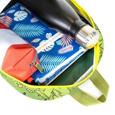 Mochila verde aberta com vários itens dentro, incluindo garrafa térmica preta, carteira azul com folhas, bolsa vermelha e caderno