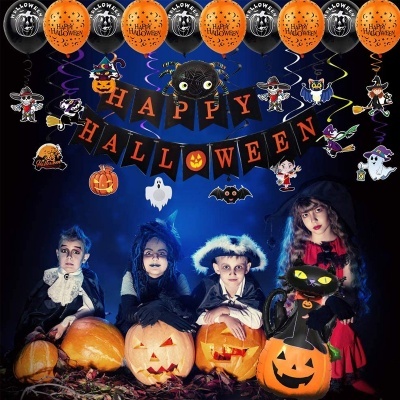 Decoração de Halloween com balões, faixa com letras, crianças fantasiadas e abóboras iluminadas